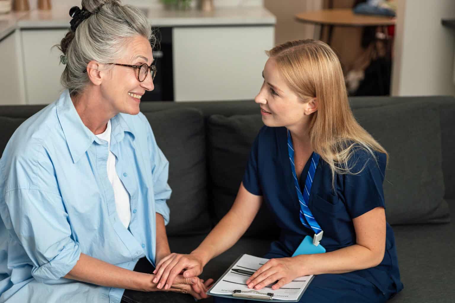 Pflegekraft spricht mit älterer Patientin im Beratungsgespräch.