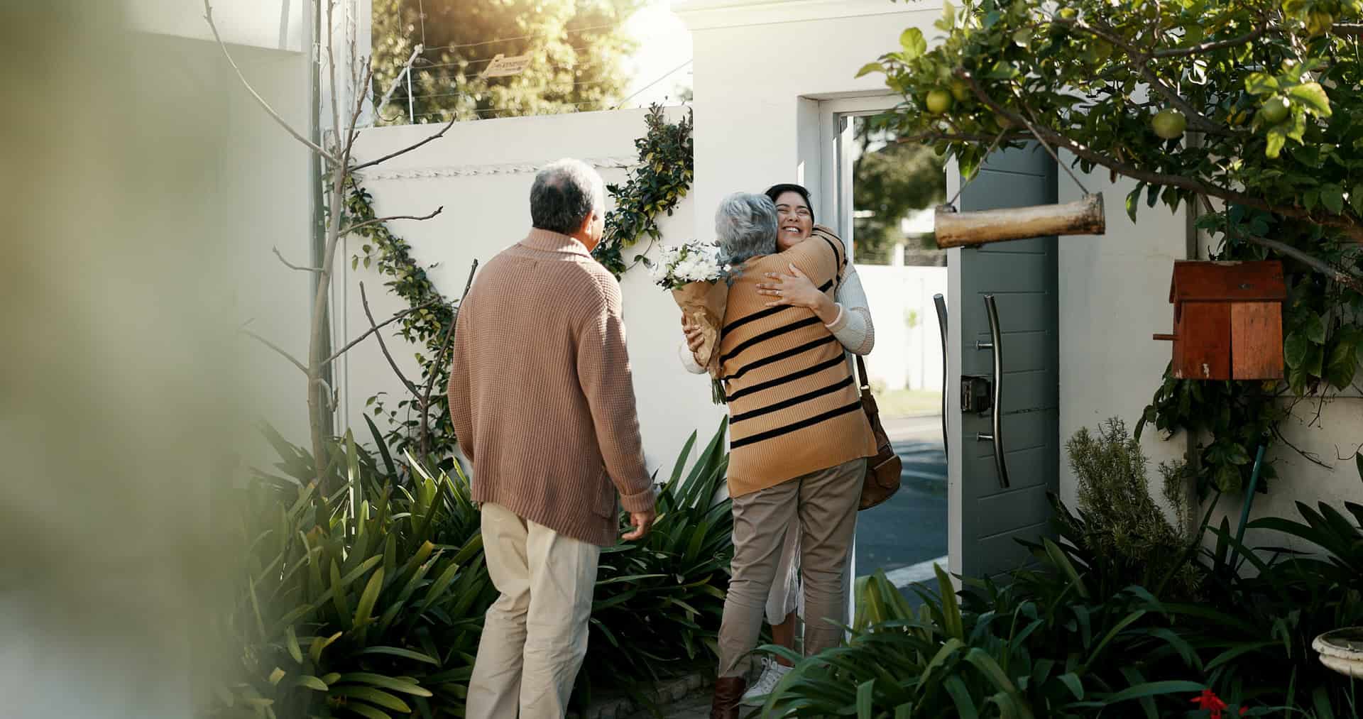 Pflegepersonal empfängt Patientin vor dem Haus, freundliche Betreuung.